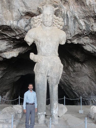 Shapur statue with a man standing in front of it